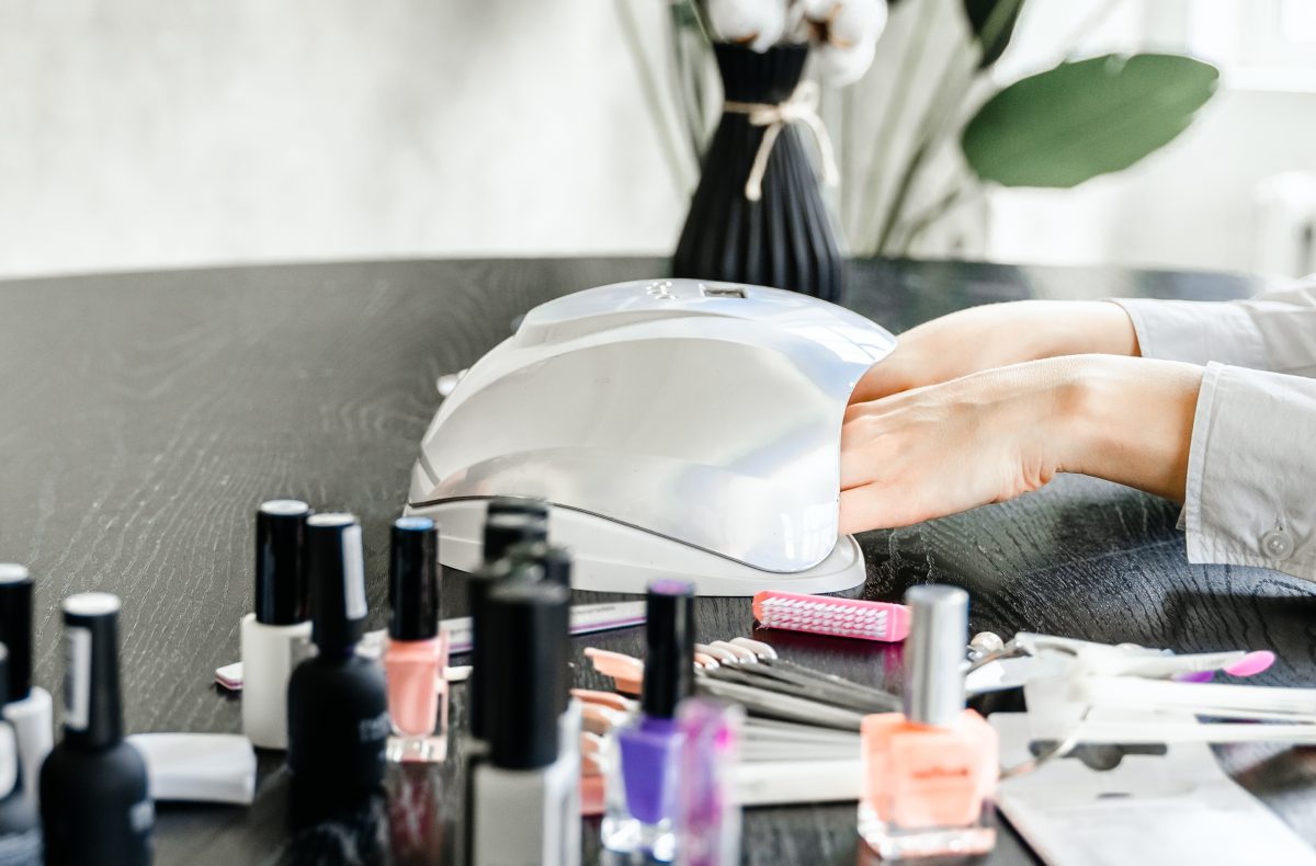 Professional master manicurist at beauty salon. Manicure service, hands treatments, procedures for nails, fingers. Multi-colored nail polish, samples palette, tattoos, cuticle oil, gel uv lamp,gloves.