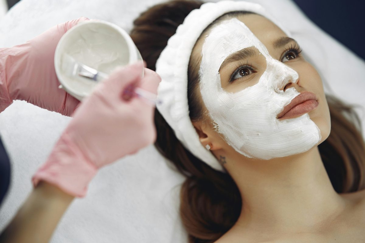 A facial technician is applying hydration treatment to a client's face at a beauty center. SPA center. facial care.