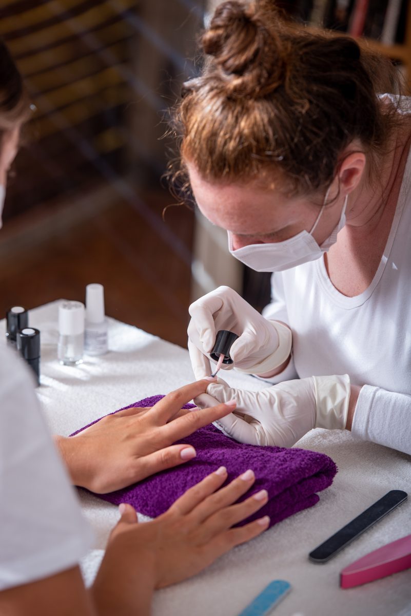 Shot of a beautician doing polish on beautiful nails. Pricing nail services. 