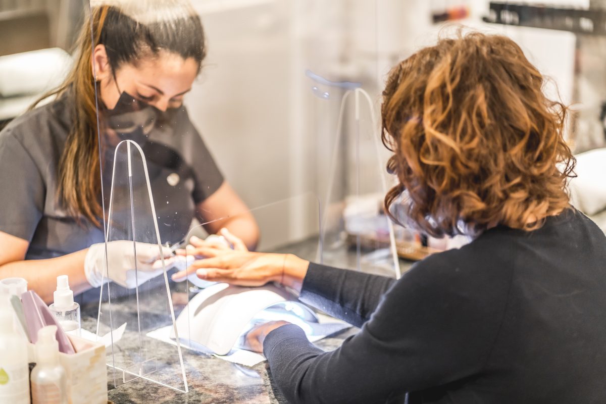 A worker with security measures working with a client. Reopening after the coronavirus pandemic. Manicure and Pedicure Salon.