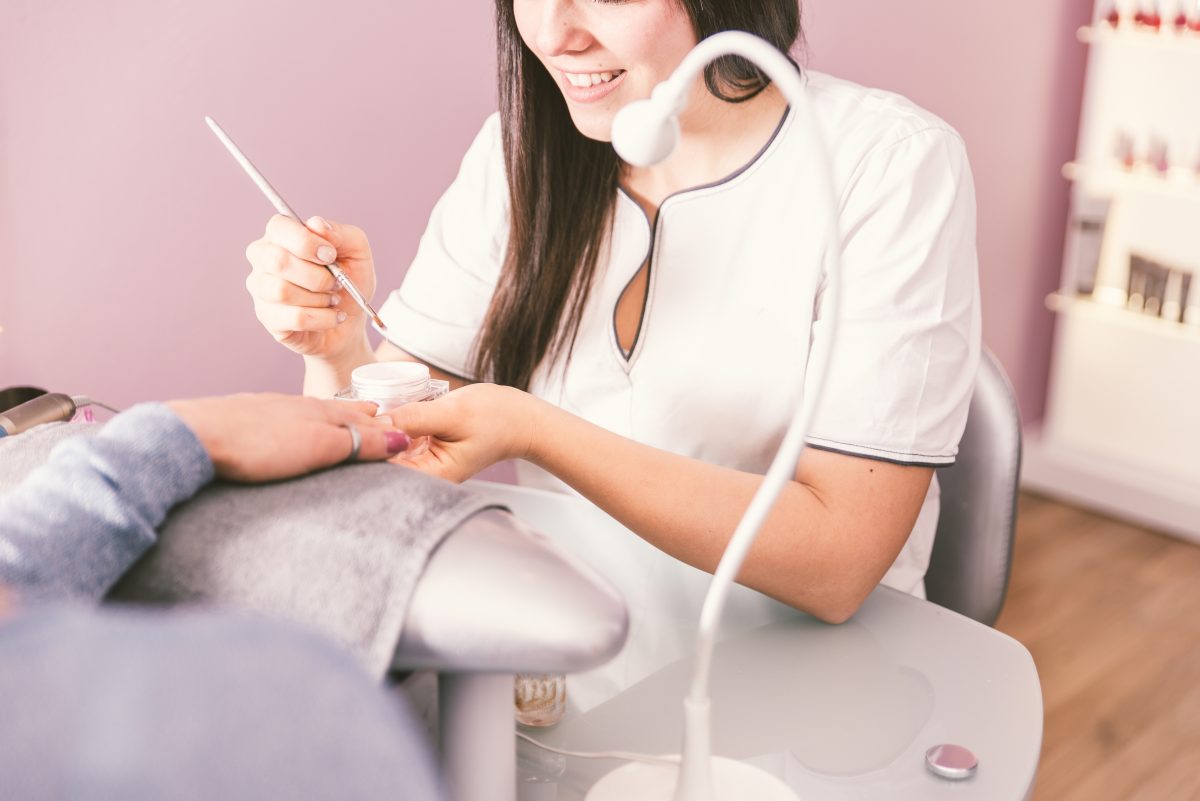 Woman making nails treatment in a beauty saloon. Beautician working with the brusher. Beauty concept.