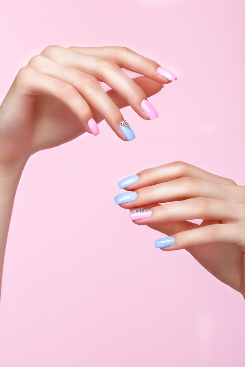 Beautiful pink and blue manicure with crystals on female hand. Close-up. Picture taken in the studio. entity spring 2025 collection. spring nail polish.