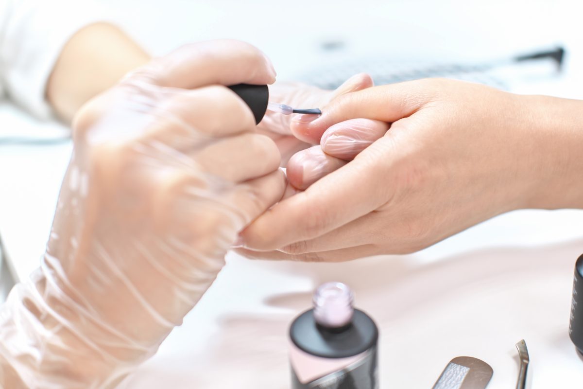 close up view of manicurist working in beauty salon. beautician applying gel polish on female nails. beauty care, professional treatment. nail care. nail enhancement.