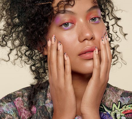 Beautiful woman with curly hair displaying her nails painted with CND SHELLAC Luxe in the Sweet Escape shade.