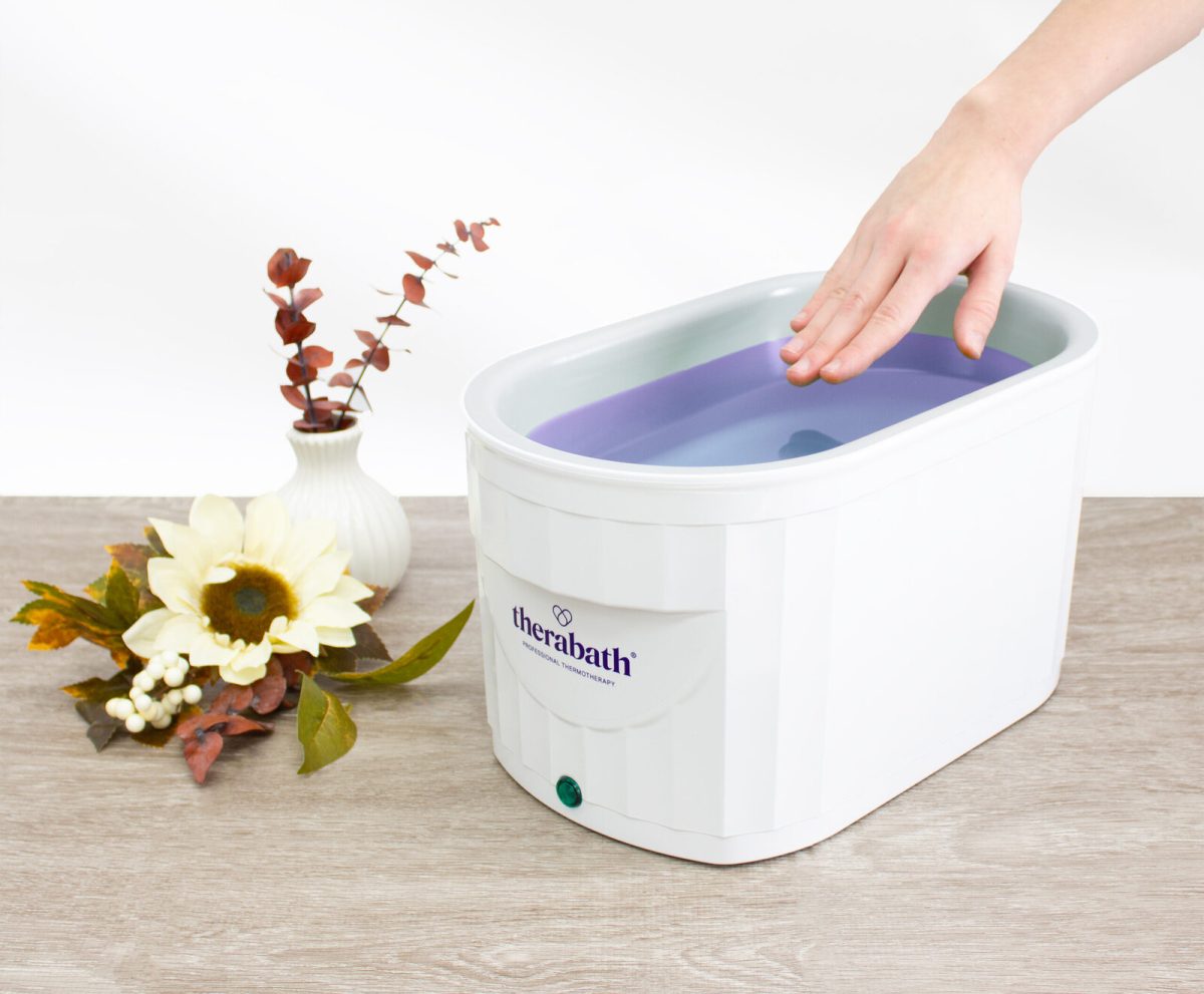 Therabath Professional Paraffin Bath – Model TB6 with Classic Paraffin. A faceless woman immerses her hand into the paraffin bath, experiencing warm and therapeutic relief.