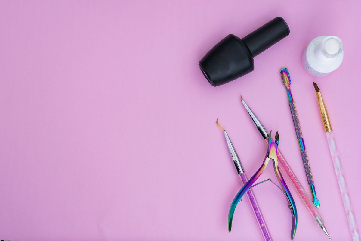 basic elements for a manicure, placed on a pink background. black and white nail polish, colored brushes, cuticle pusher and cuticle nippers items for sale and marketing in the aesthetic beauty market. nail polish tools. nail manicure. nail salon tools.