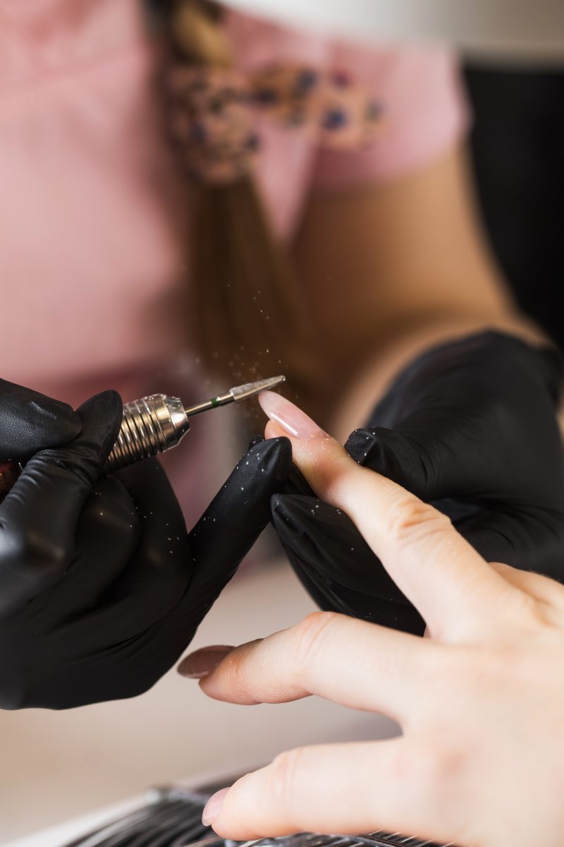 A manicurist removes gel polish from nails using a milling cutter. Hardware manicure close-up. Coating shellac on nails. High quality photo