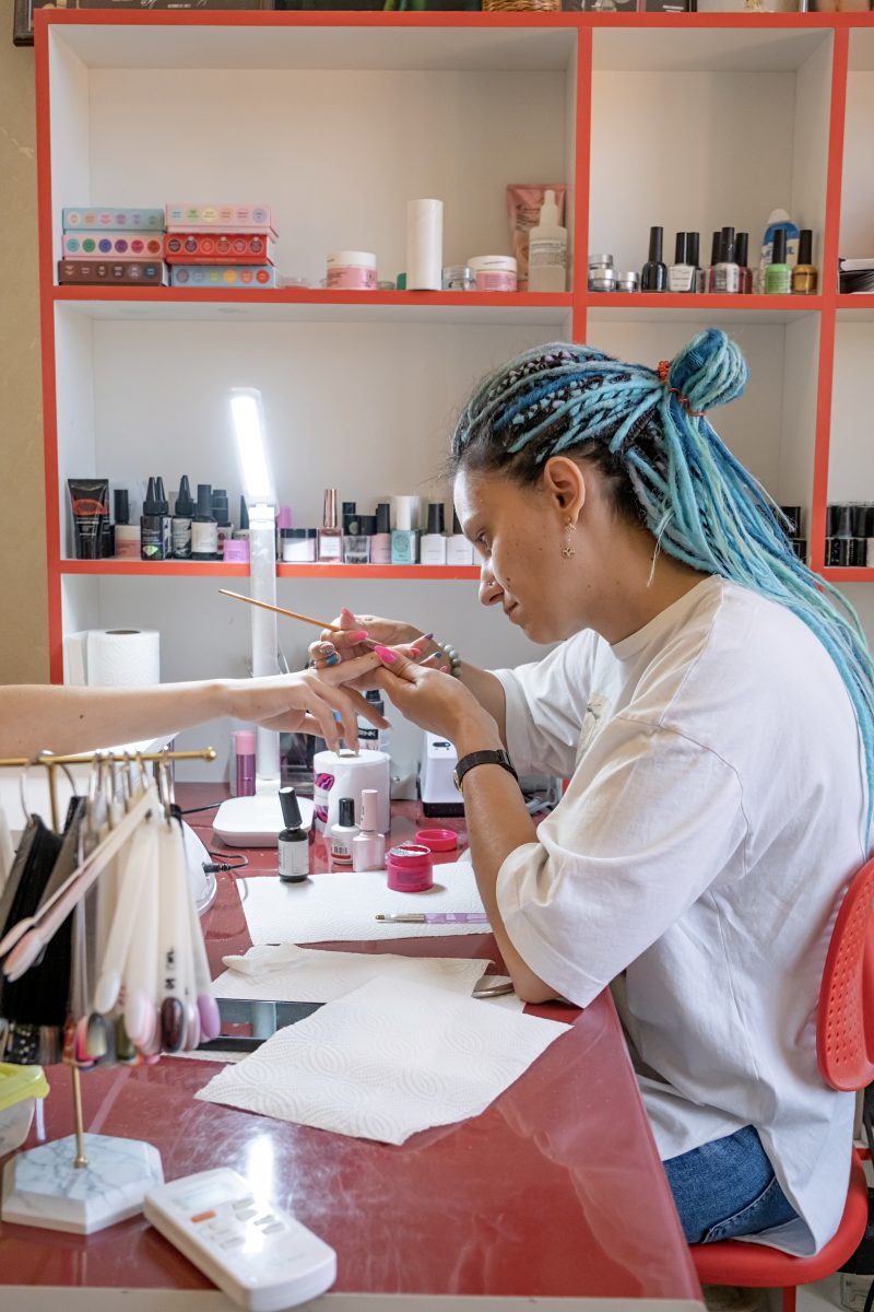 Nail Innovations for 2024. closeup of manicurist doing nail art to a client. New products. New nail tools. New trends. Nail trends. From above of crop unrecognizable manicurist doing nail art for female client in beauty salon.