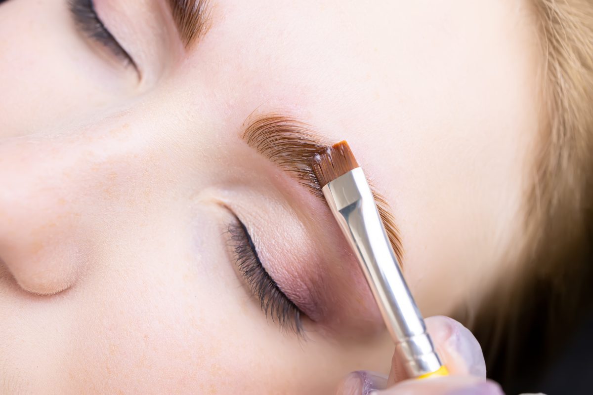 applying hair dye to the eyebrows of the model
