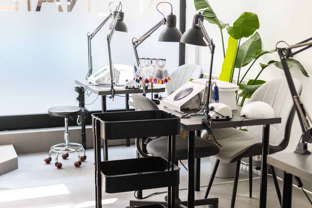Modern table with nails color palette and lamp situating in salon. Workplace for manicure. Interior