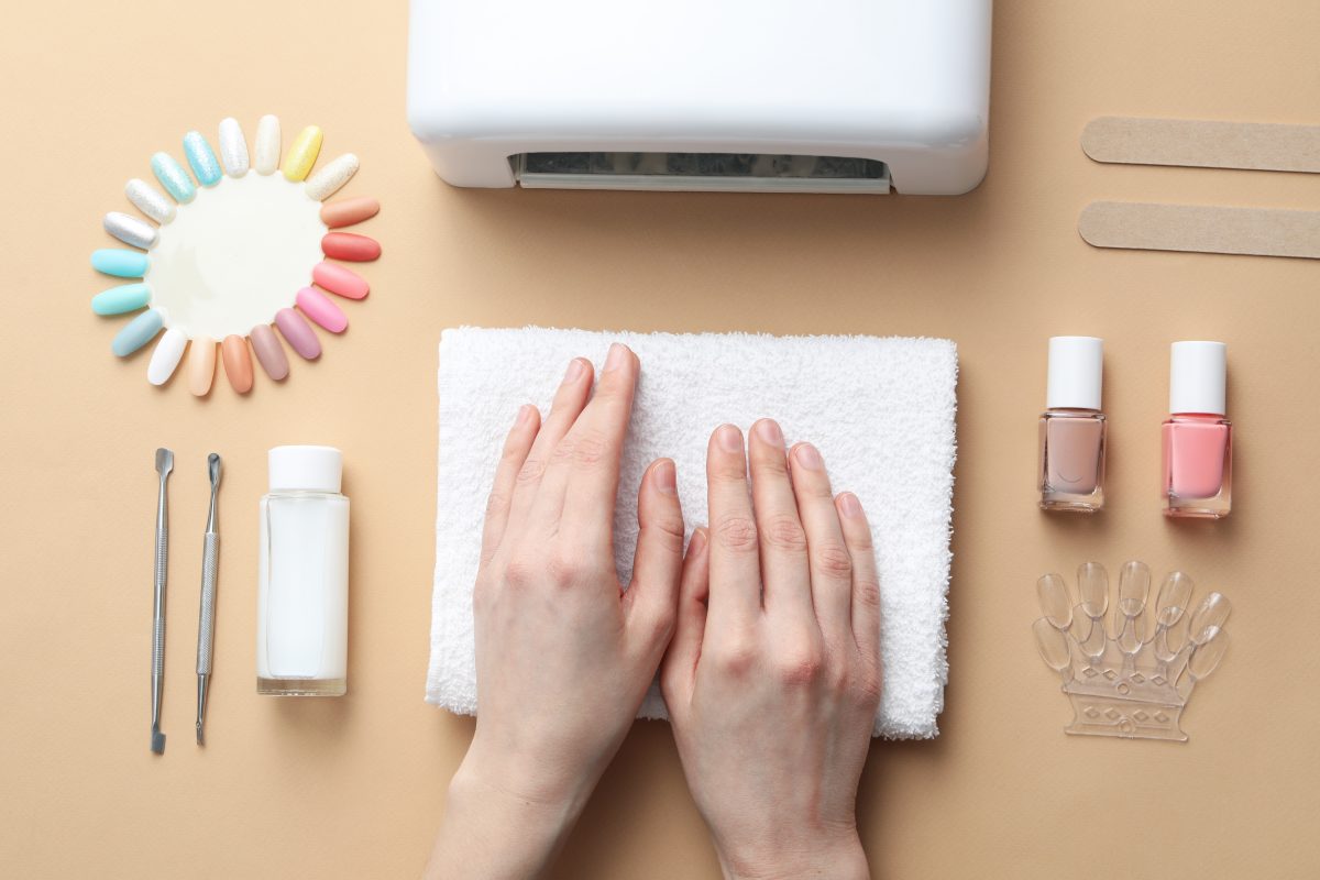 Tools for nail art and female hands on beige background, top view. Manicure and Pedicure Towels