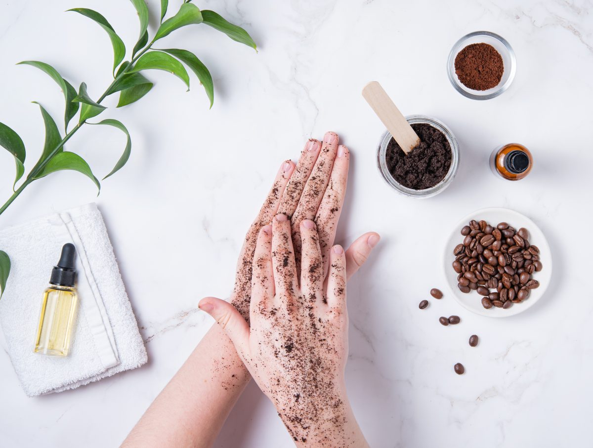 Spa concept. A young woman does a hand massage with a homemade coffee scrub from recycle capsule with olive oil on marble background. Top view. 
