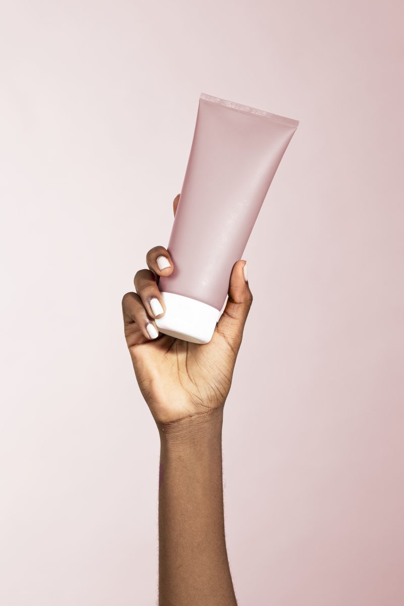 Black woman holding a beauty cream tube