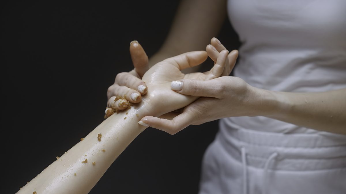 Best Practices for Applying Pre-Wax Products. Close-up of masseur rubbing scrub on hand. Action. Gentle movements of masseur on client's hand. Beautiful massage movements and rubbing.