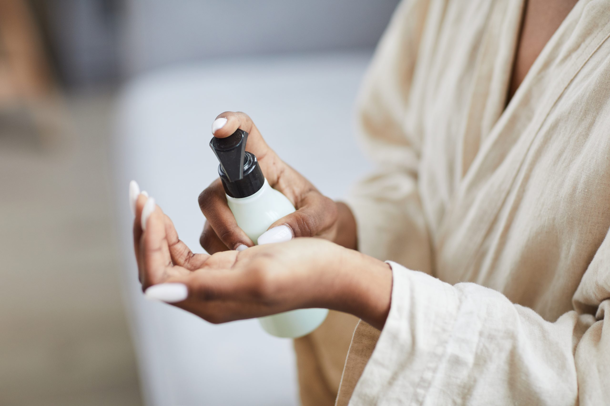 Close up of beautiful African-American woman using hand cream or moisturizer, copy space