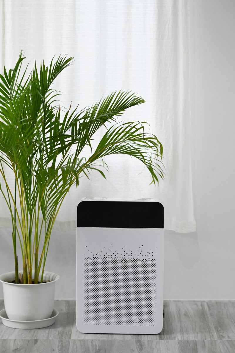 Air Purification Systems. White modern air purifier on floor in bright living room for filter and cleaning removing dust PM2.5.