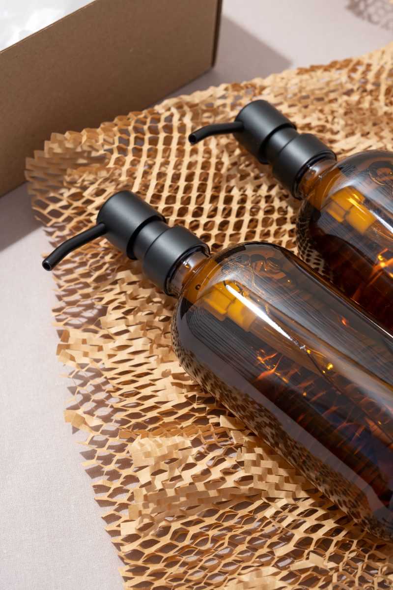 The Best Dry Body Oils for Professional Use. amber glass cosmetic bottles dispensers in box , unpacking eco friendly gift on earthy colored background