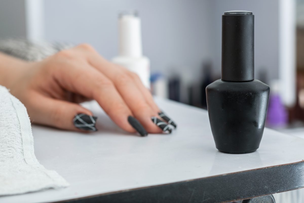 close-up of matte black nail polish with white nail designs. nail polish. gel polish. nail enhancement.