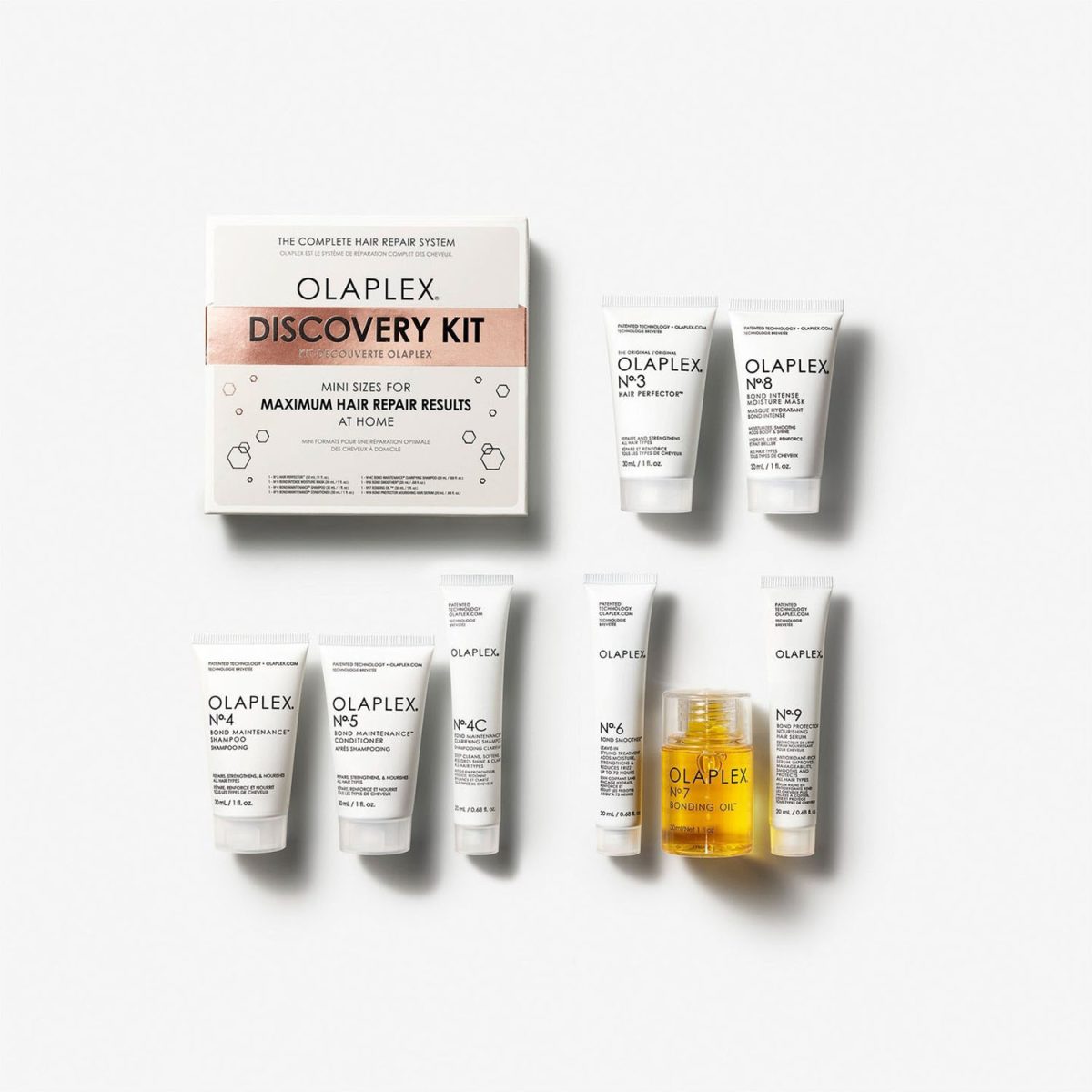 Olaplex Discovery Kit, products. hair treatment. hair care. The kit includes mini sizes of Olaplex No. 3 Hair Perfector, No. 4 Bond Maintenance Shampoo, No. 5 Bond Maintenance Conditioner, No. 8 Bond Intense Moisture Mask, No. 9 Bond Protector Nourishing Hair Serum, and No. 7 Bonding Oil. The packaging emphasizes its purpose as "The Complete Hair Repair System," designed for maximum hair restoration. The products are displayed in front of a branded box labeled "Olaplex Discovery Kit."