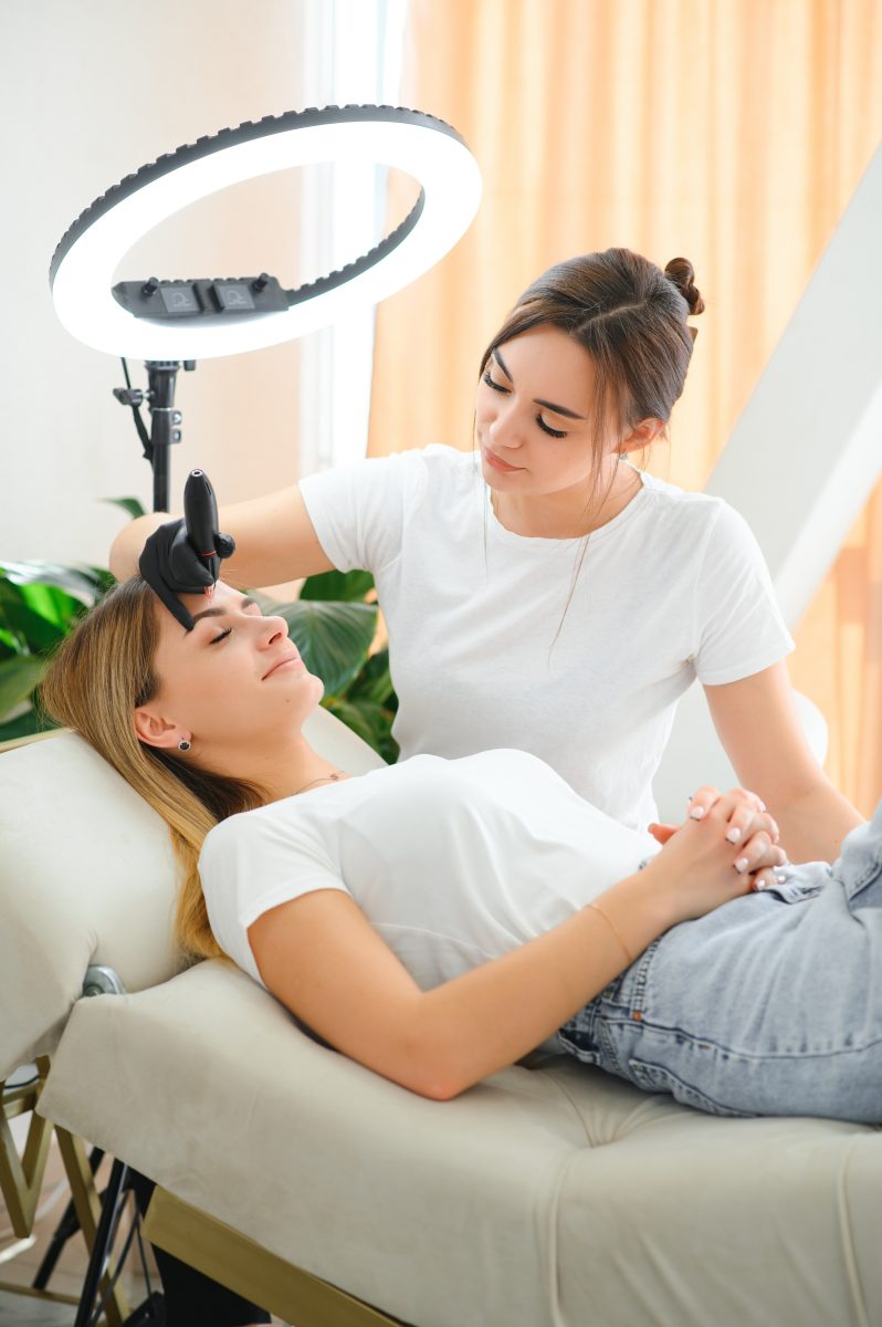 Process of creating permanent brow makeup with a machine at beauty salon. facial beds. spa facial beds. massage beds. salon treatment beds.