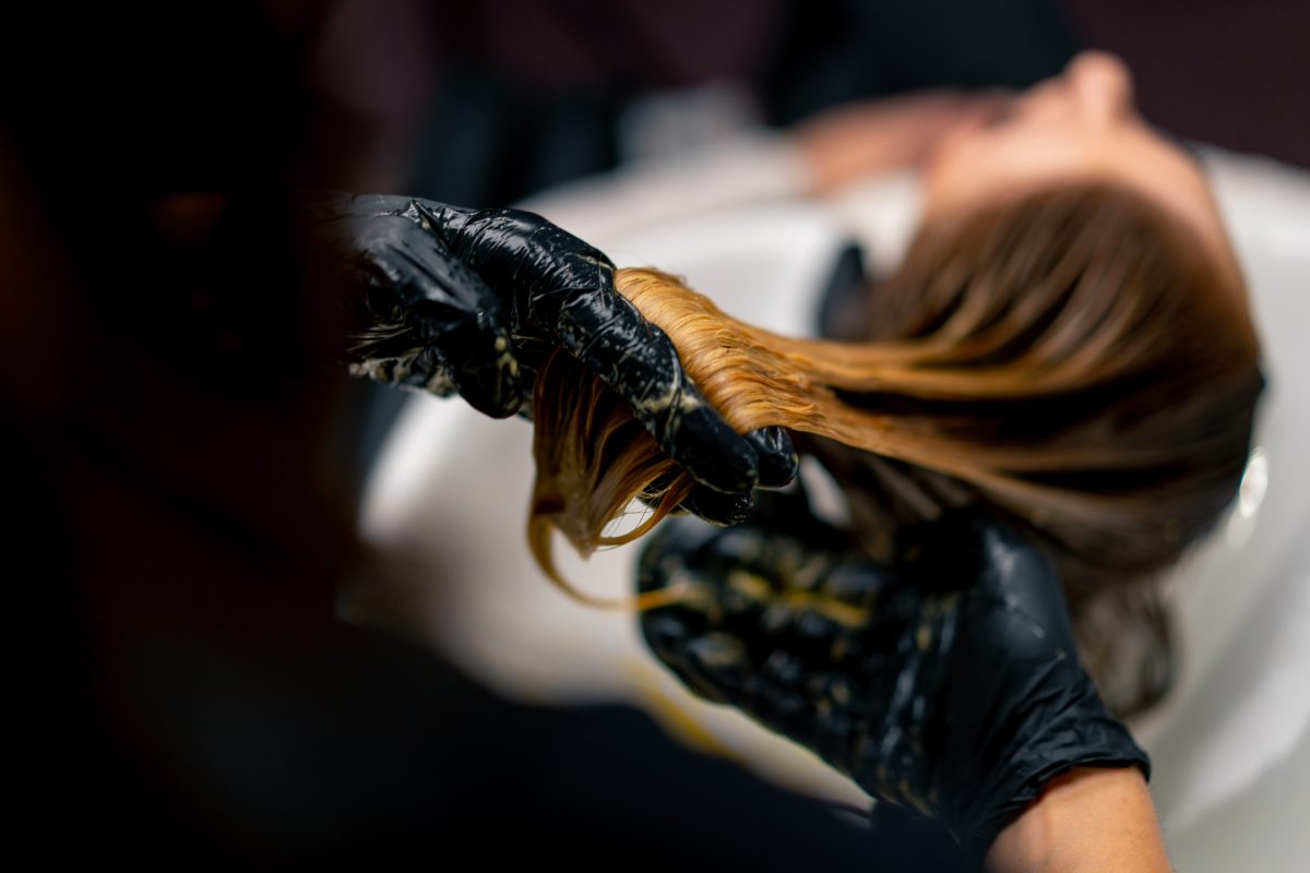 close-up of a hairdresser applying paint to a client's wet hair in beauty salon makeover