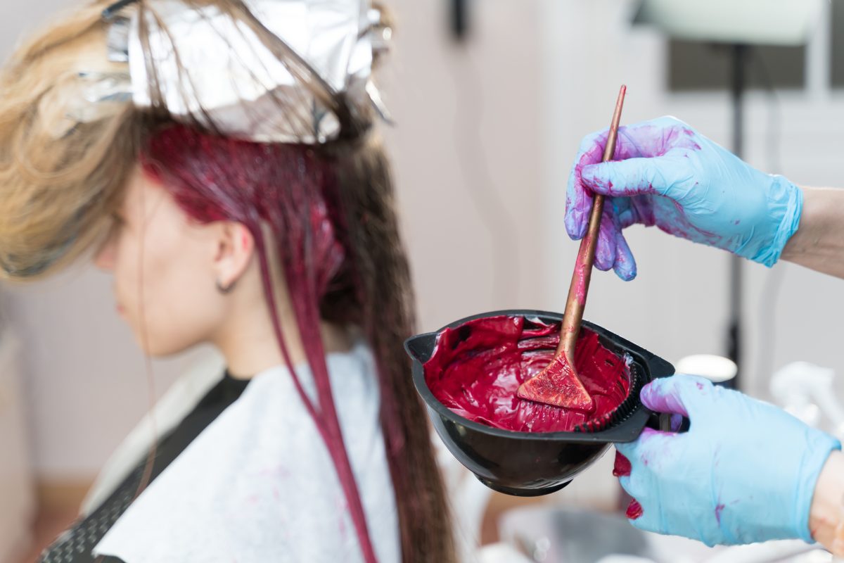 Best Hair Dye Products for Salons. hairdresser makes hair coloring to a young girl.