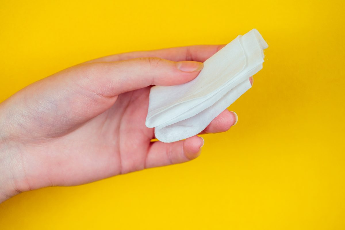 hand holds a white napkin on a yellow background