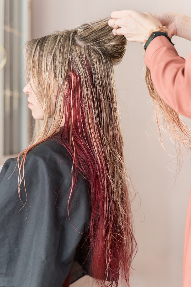 A girl with long wet colored hair sits in a barber chair.
