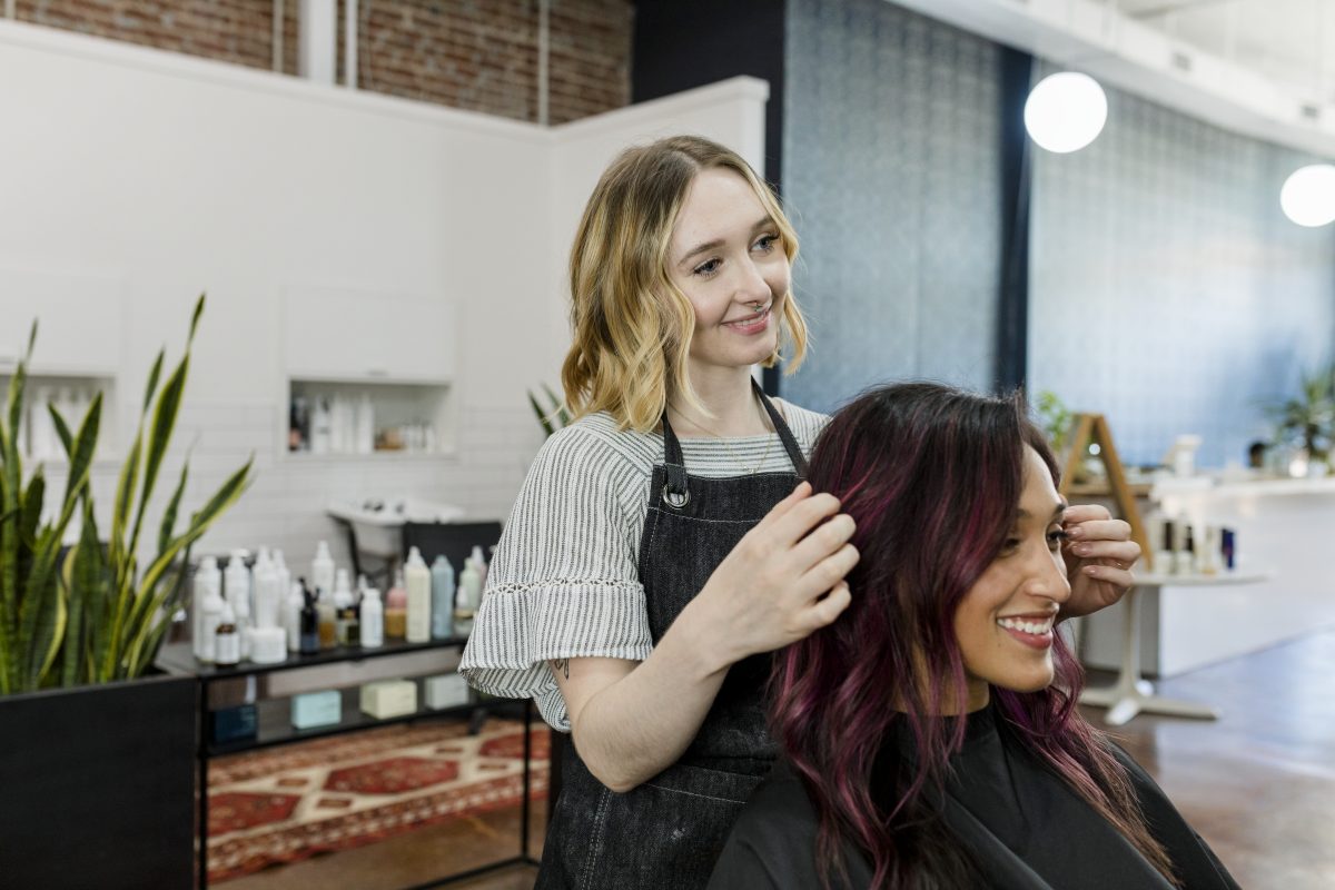 Hairstylist giving a haircut to a customer at a beauty salon. Colored Hair Care.