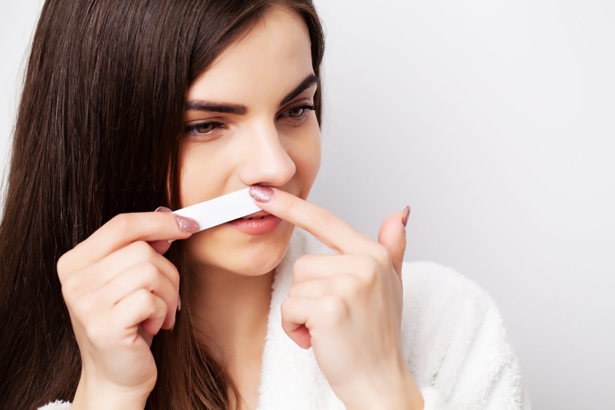 Care concept, woman holding stripe with wax to remove facial hair.