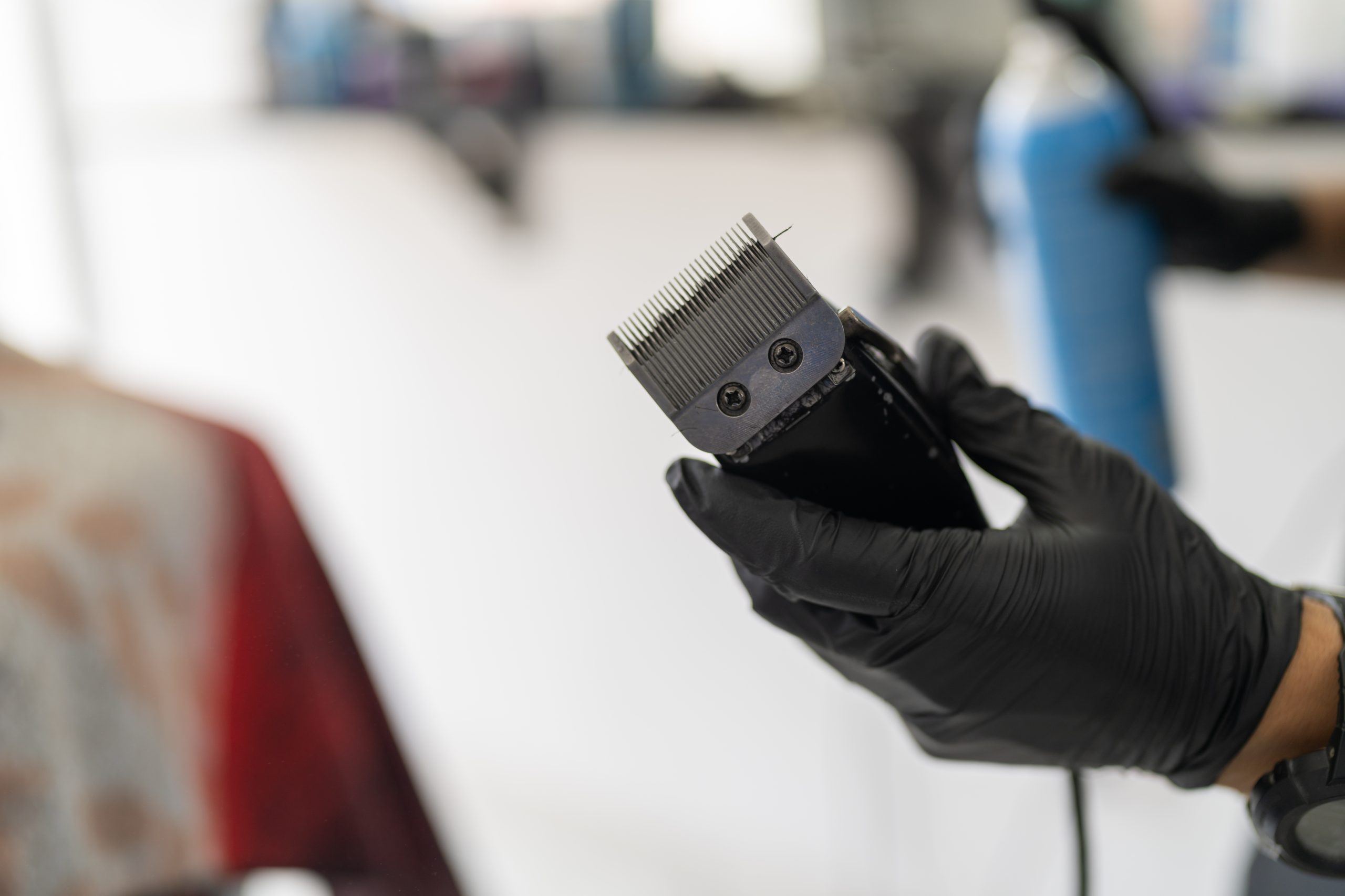 Close-up and focus on gloved hands of a barber with an electric razor