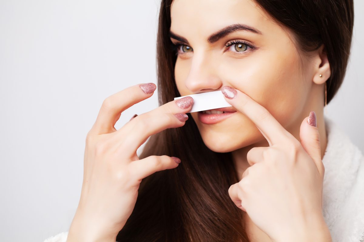 Young woman doing waxing in the area above the eyebrows.