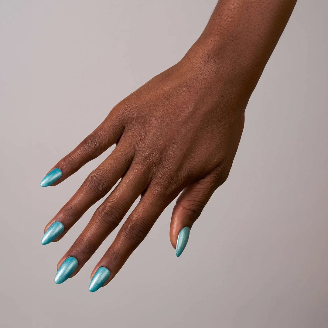 Hand with long, almond-shaped nails in a shimmery light blue, showcasing the CND Shellac 'Sleeping Mask' shade from the Quiet Luxury Spring 2025 collection.
