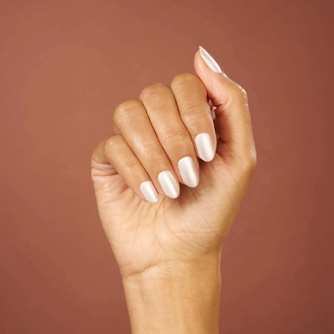 Hand with elegant, long almond nails coated in CND Shellac 'Silk Thread', a beautiful beige taupe with a subtle pink shimmer from the new Quiet Luxury Spring 2025 collection.