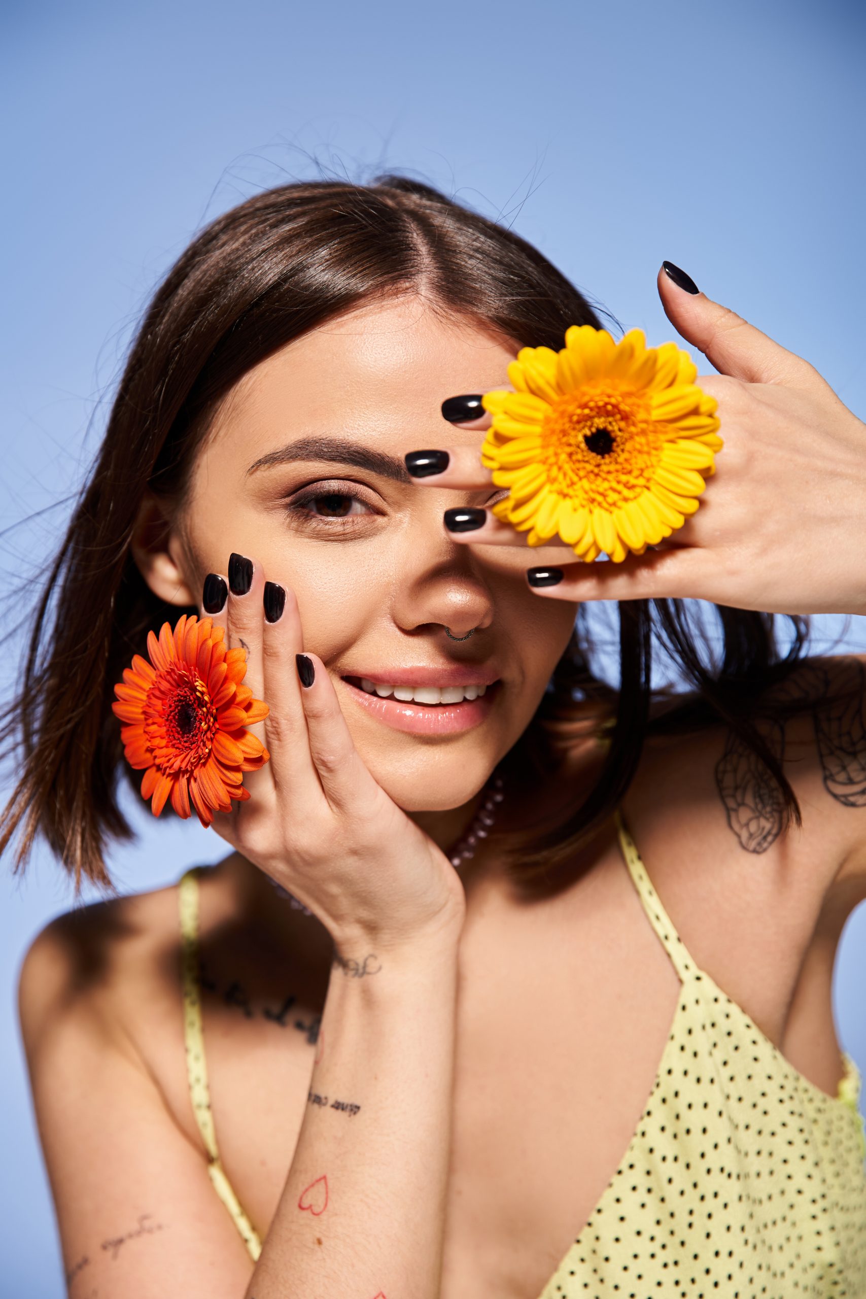Summer 2025 nail colors. Summer vibes. Nail summer colors. A young woman with brunette hair holds a delicate flower in front of her face, showcasing elegance and grace.