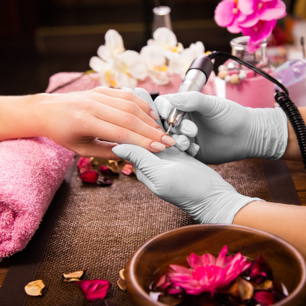 Spring nail colors. Closeup finger nail care by manicure specialist in beauty salon. Manicurist clear cuticle professional electric tool for manicure and pedicure. Spring shades.