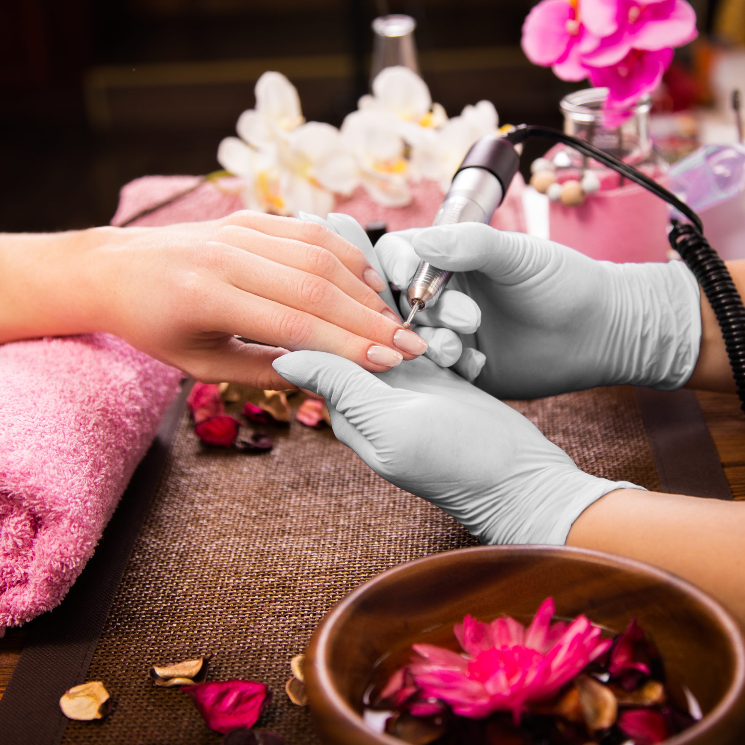 Spring nail colors. Closeup finger nail care by manicure specialist in beauty salon. Manicurist clear cuticle professional electric tool for manicure and pedicure. Spring shades.