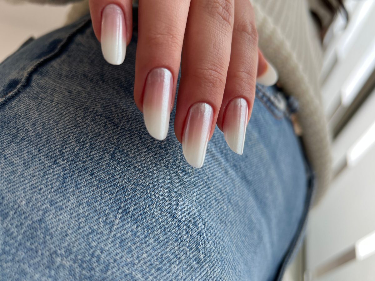 A closeup image of a female hand with professionally painted nails in natural tones. Spring nails. Spring 2025 nails.