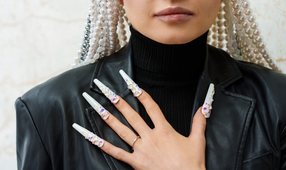Cropped photo of a female artist showing long and decorated fake nails. Spring nails. Spring 2025 nails.
