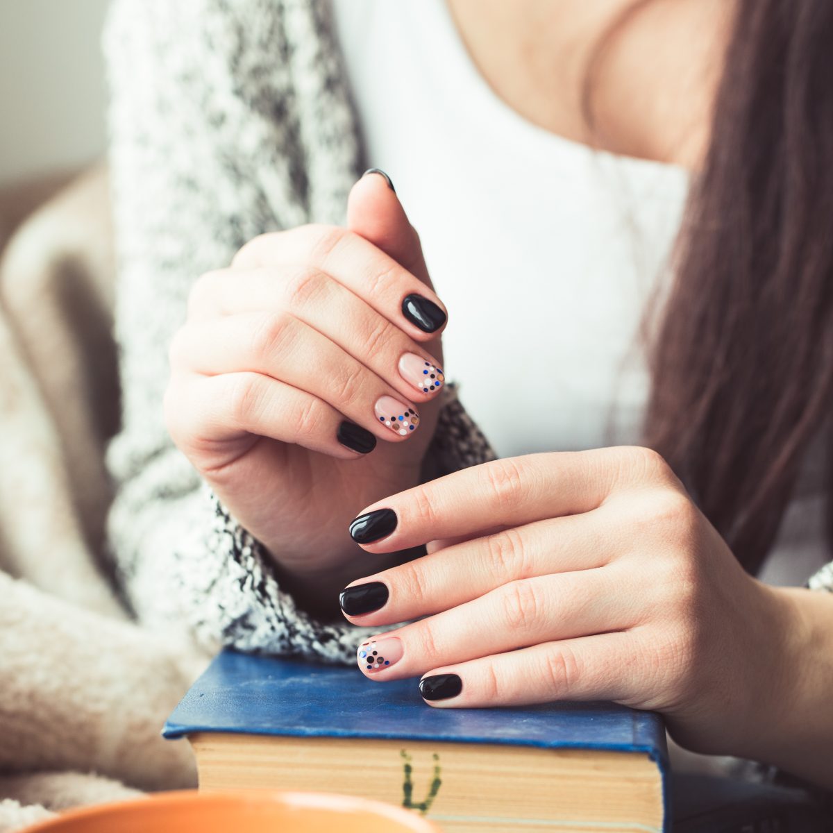 Young woman reading book, close-up, on home interior