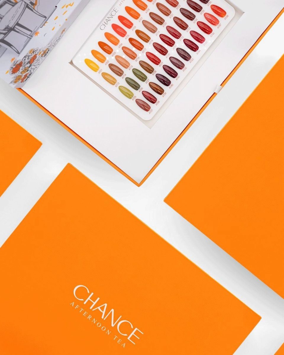 A high-angle close-up of the open Chance "Afternoon Tea" Gel Full Kit 48 Colors, highlighting its 48-color swatch board. The swatches display a rich autumnal palette including golden yellows (A01-A05), various burnt oranges (A06-A12), earthy olive greens (A13-A18), and deep burgundies and plum reds (A40-A48). Partially visible in the top left is the illustrated tea party scene from the lid, and the bottom left and right show the vibrant orange closed boxes of other Chance "Afternoon Tea" collections. Chance Creation Collections