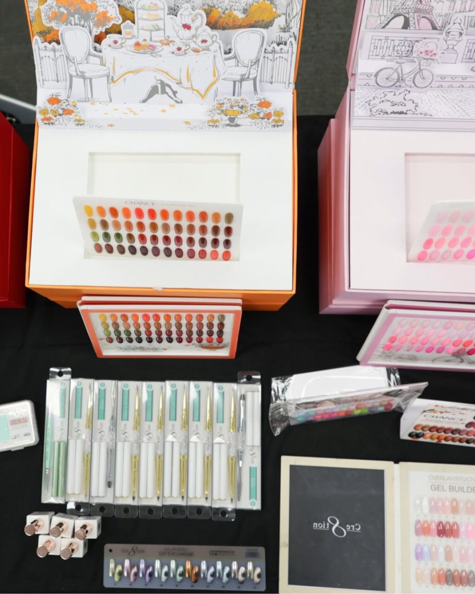 Retail display of Chance Creation Gel Polish Collections (Afternoon Tea and Pink Iconic) alongside various professional nail art tools and supplies. The table features multi-colored Cat Eye magnetic pigments/pens and swatches, Gel Builder display tips, and the 48-shade swatch boards from the main gel polish kits. This shows a complete inventory setup for a professional nail salon. Chance Creation Collections