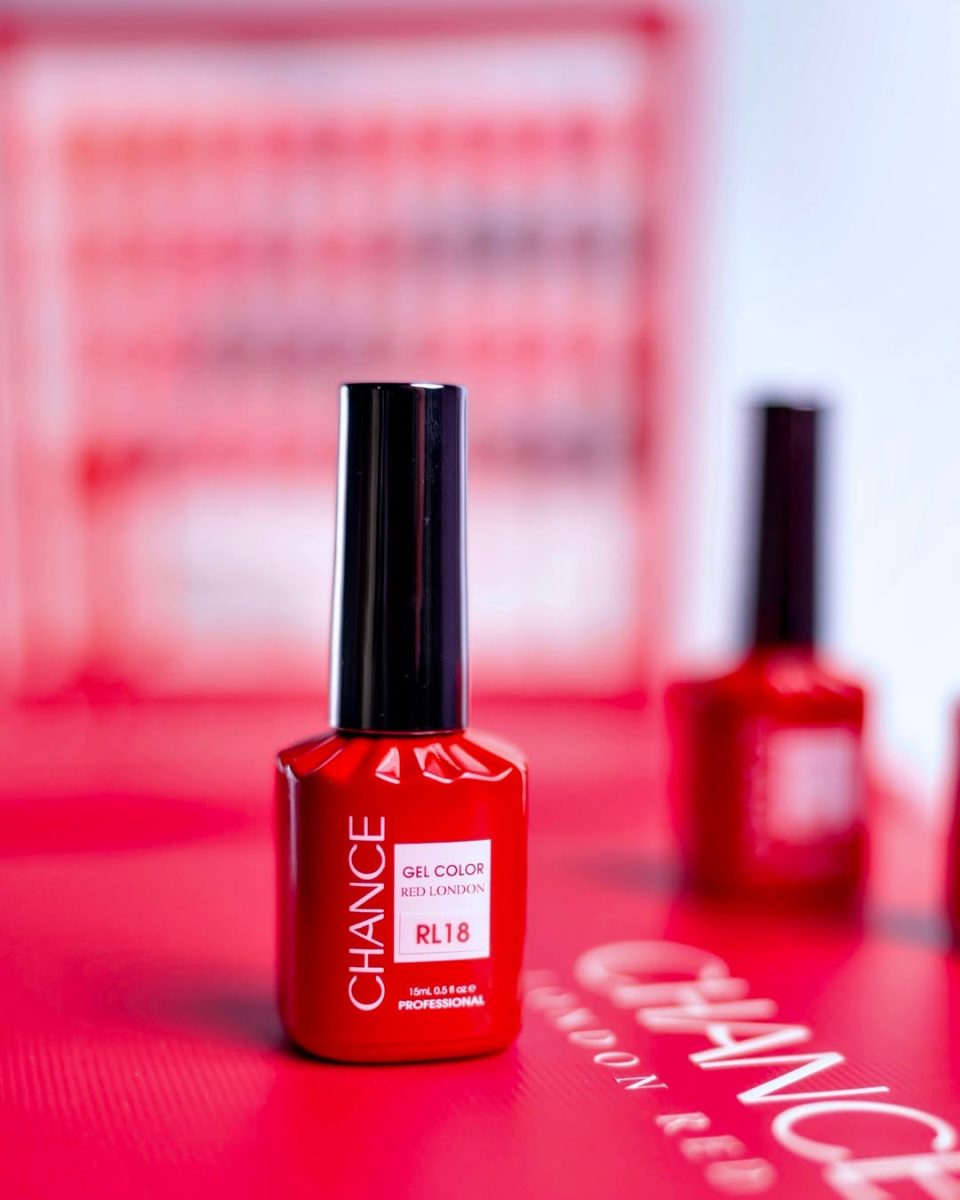 Macro close-up of a single 15ml Chance "Red London" Gel Color bottle, shade code RL18. The high-pigment red polish in the foreground is sharply focused, emphasizing the glossy finish and the professional label, with other out-of-focus bottles visible on the red background.