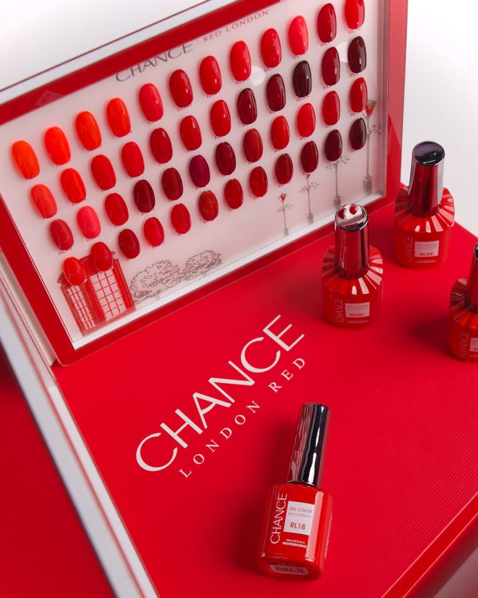 Close-up of the Chance "London Red" 48-shade swatch board revealing the full spectrum of red gel colors, from bright orange-reds to profound burgundies. Several individual 15ml professional gel polish bottles in shades like RL18 are displayed on the vibrant red collection box, highlighting the high-gloss, long-lasting formula. Chance Creation Collections