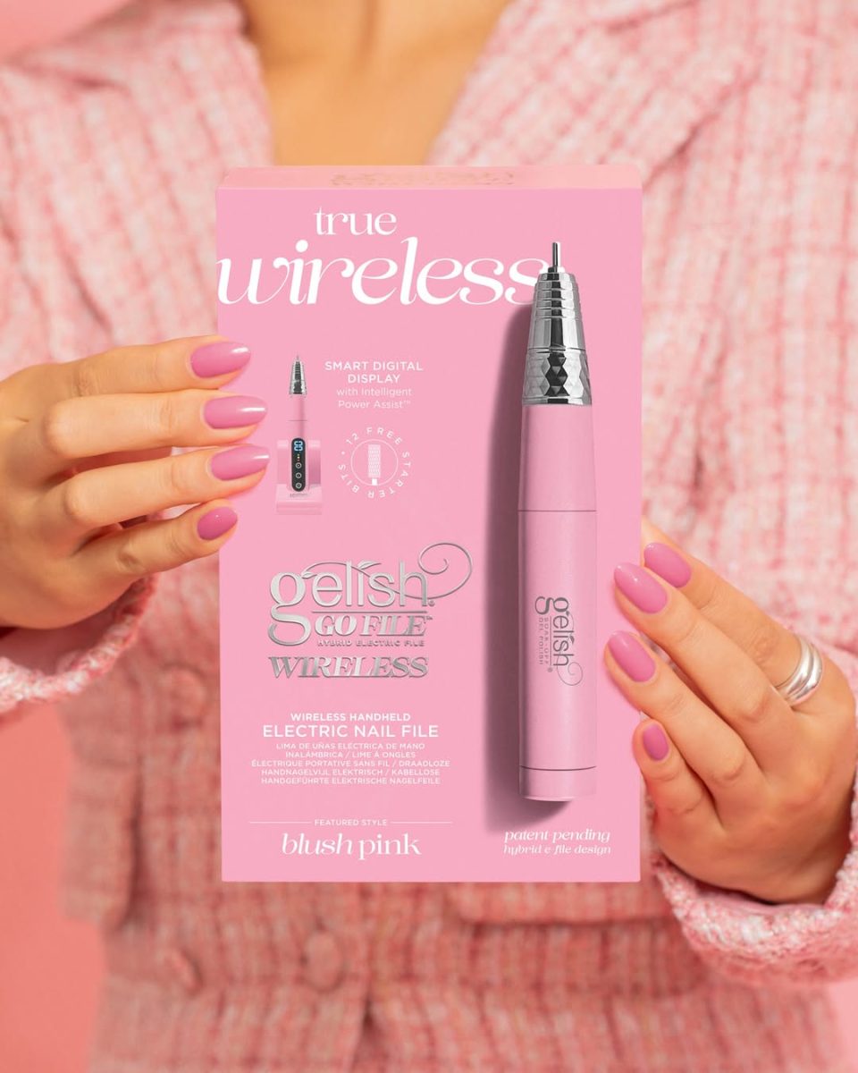 Blush Pink Gelish Go File Wireless E-File box held by a person with matching pink nails and outfit. The packaging highlights features like wireless design, smart digital display, rechargeable battery, and patented Mag Lock docking station. Ideal for nail professionals seeking a stylish, high-performance cordless nail drill.