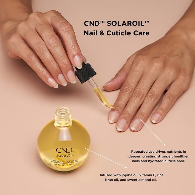 Close-up of hands applying CND SolarOil with a dropper, highlighting that the product is infused with jojoba oil, vitamin E, rice bran oil, and sweet almond oil to drive nutrients deeper, resulting in stronger, healthier nails and a hydrated cuticle area.