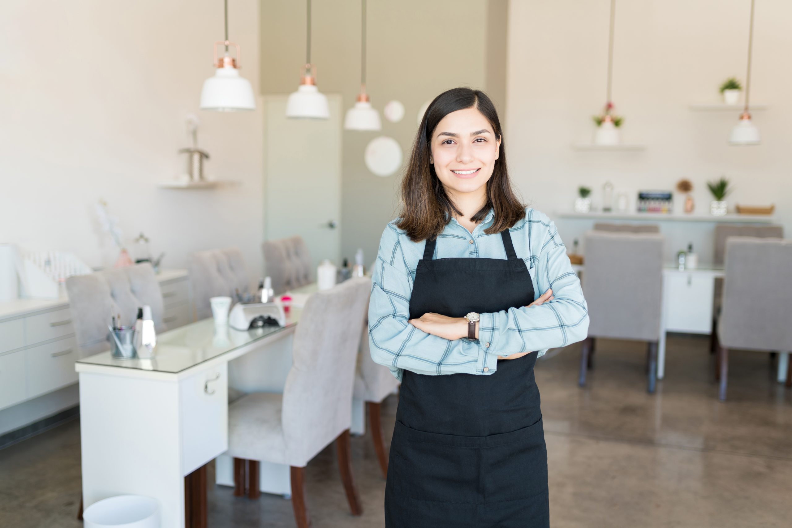 Portrait of beautiful female cosmetician with arms crossed standing at beauty salon