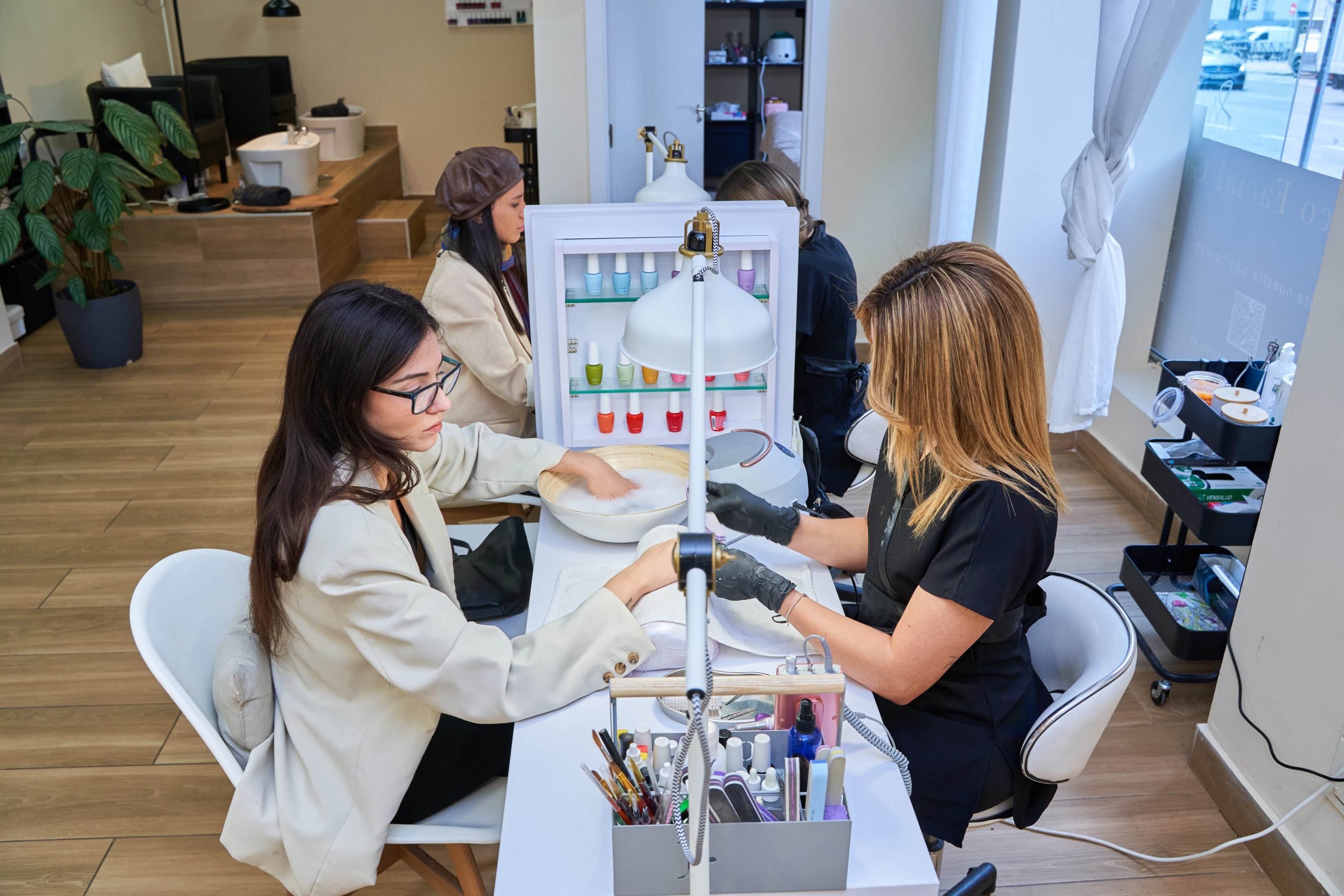 Young girls use the service of Express manicure in the salon of the shopping center.