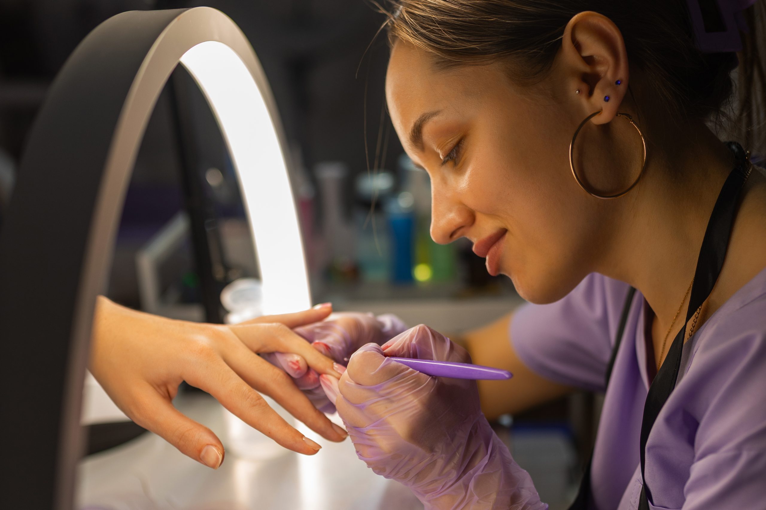 A technician using a professional electric file (e-file) for precise cuticle prep, a core skill in Advanced nail training programs