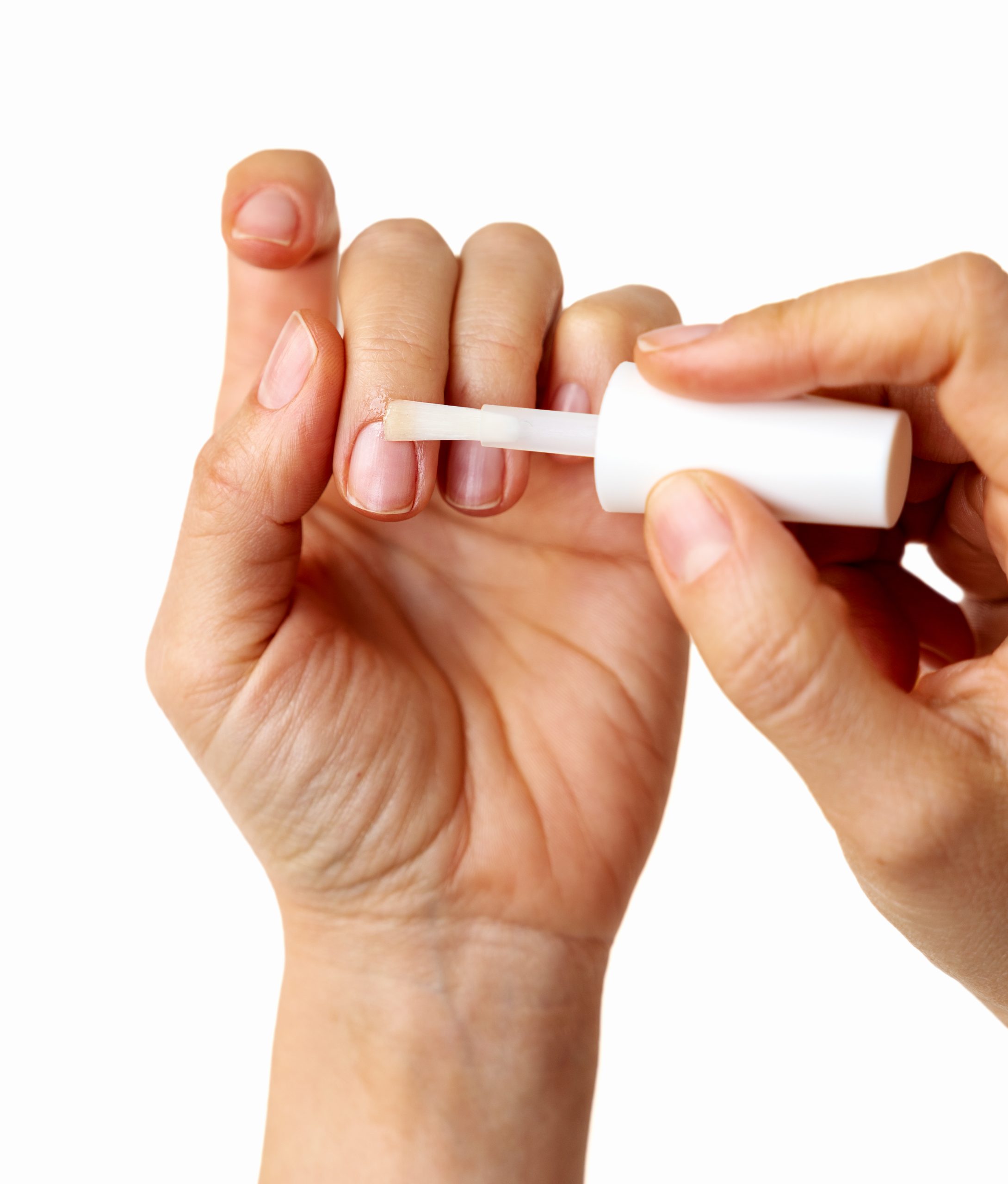 Detailed view of a brush applying a liquid nail tape or cuticle guard to skin to prevent nail polish staining during nail art.